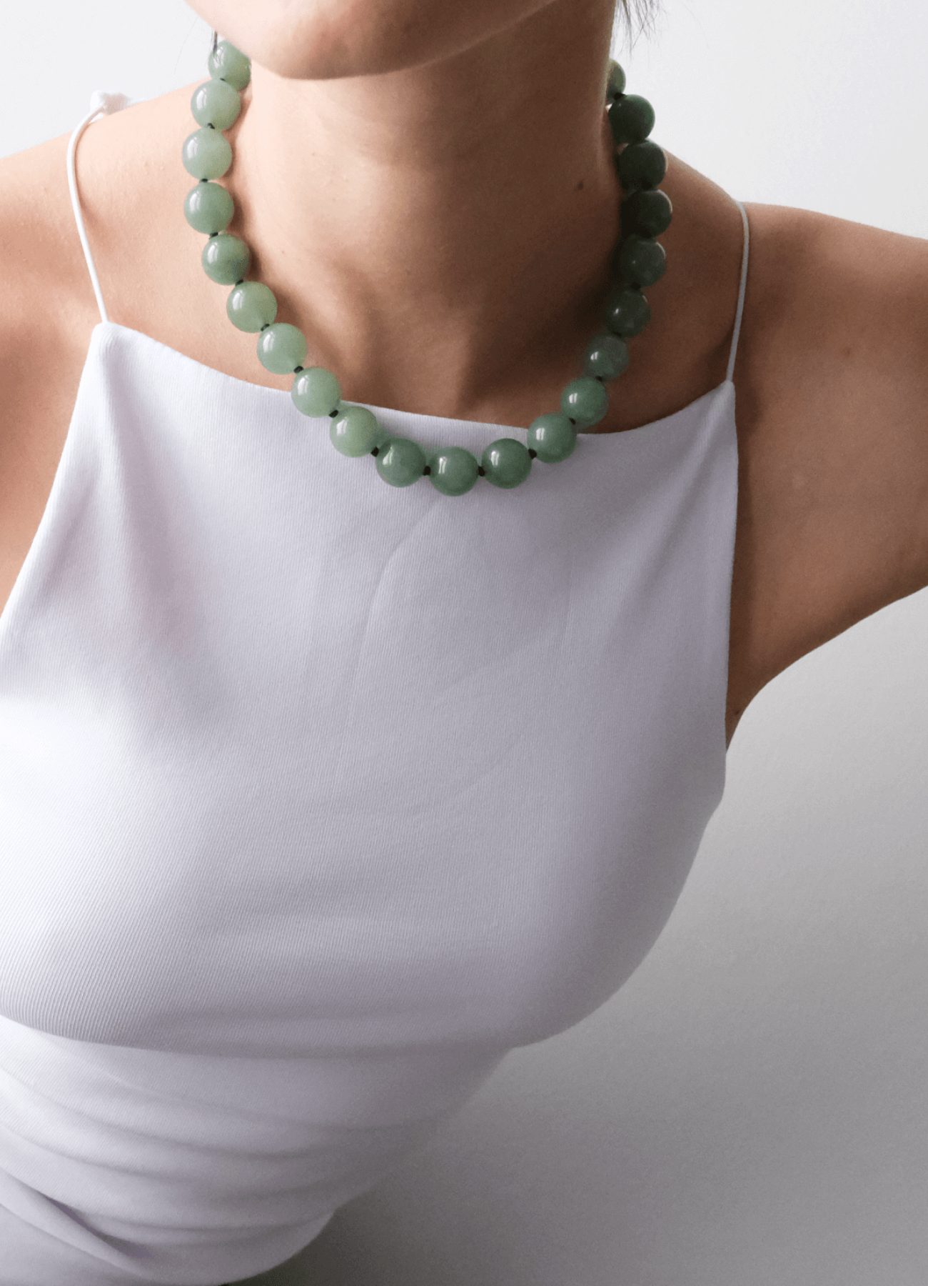 neckline with a white top Wearing a green Aventurine gemstone necklace 