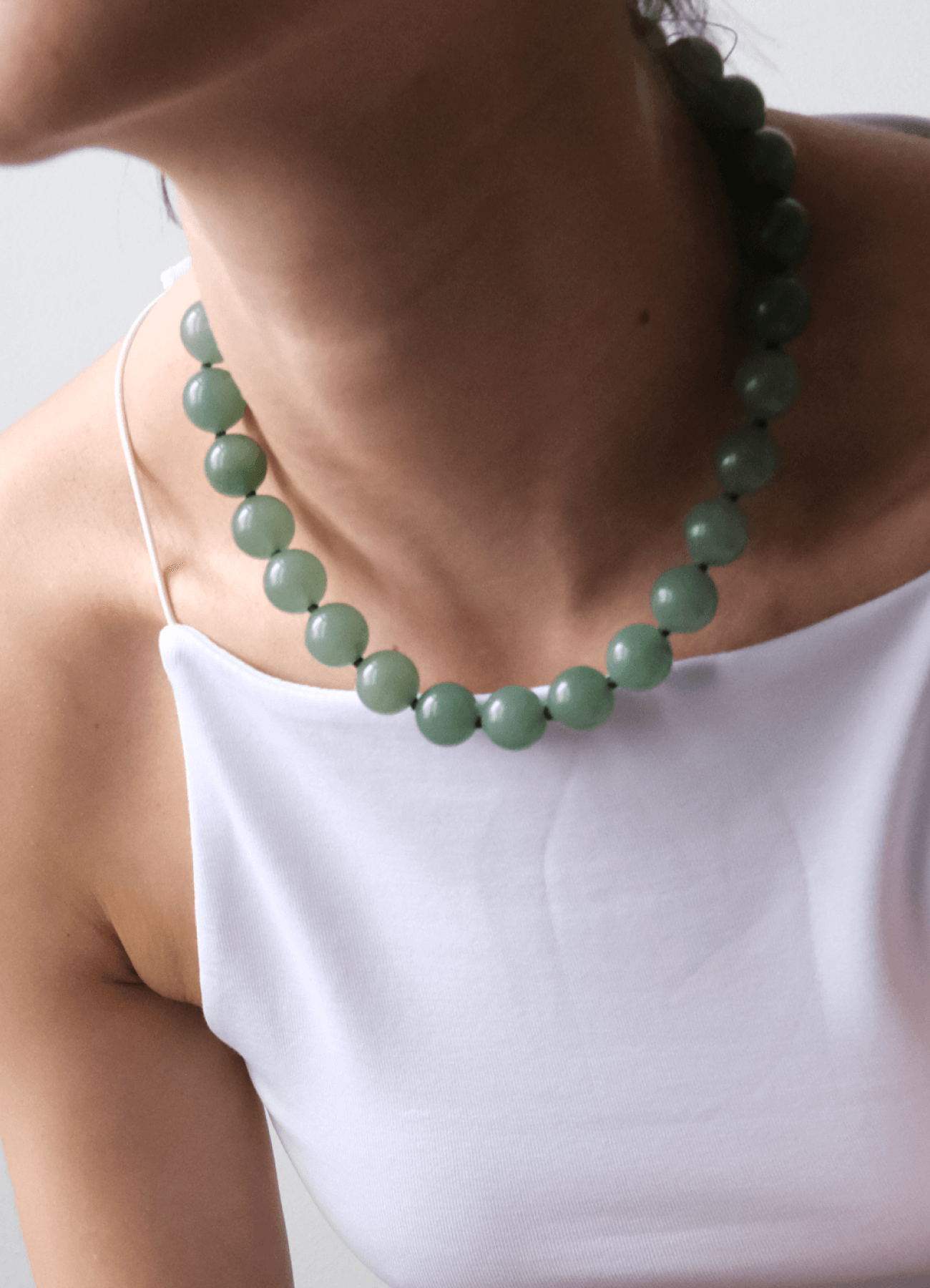 neckline with a white top Wearing a green Aventurine gemstone necklace 