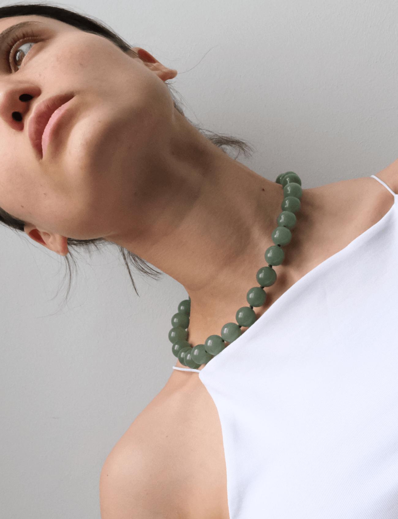 neckline with a white top Wearing a green Aventurine gemstone necklace 