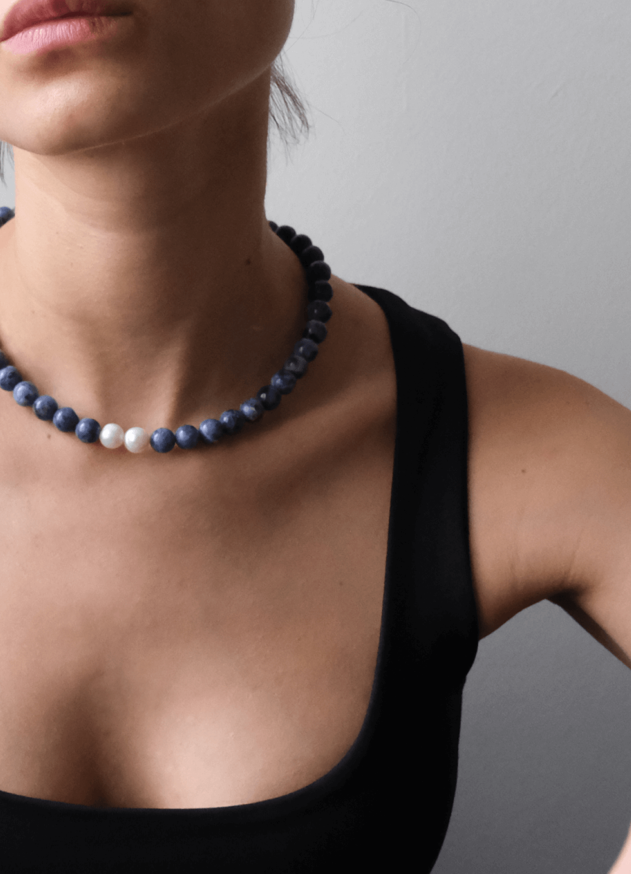  neckline with a black top Wearing a blue Sodalite gemstone necklace 